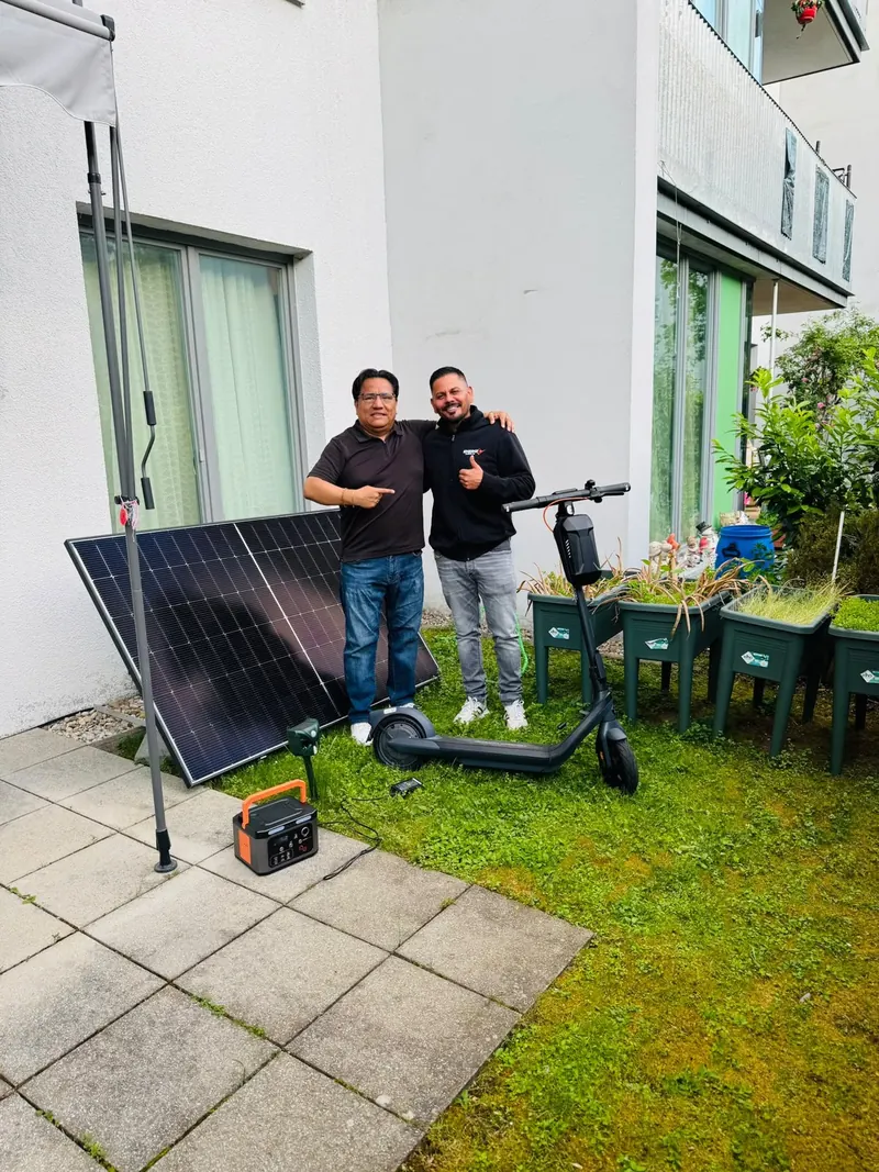 Kunde mit EcoHome-Team vor Solarmodul, Powerstation und E-Scooter im Garten